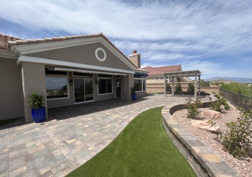 A patio with grass and a pergola in the middle of it.