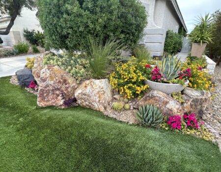 A garden with flowers and rocks in the grass.