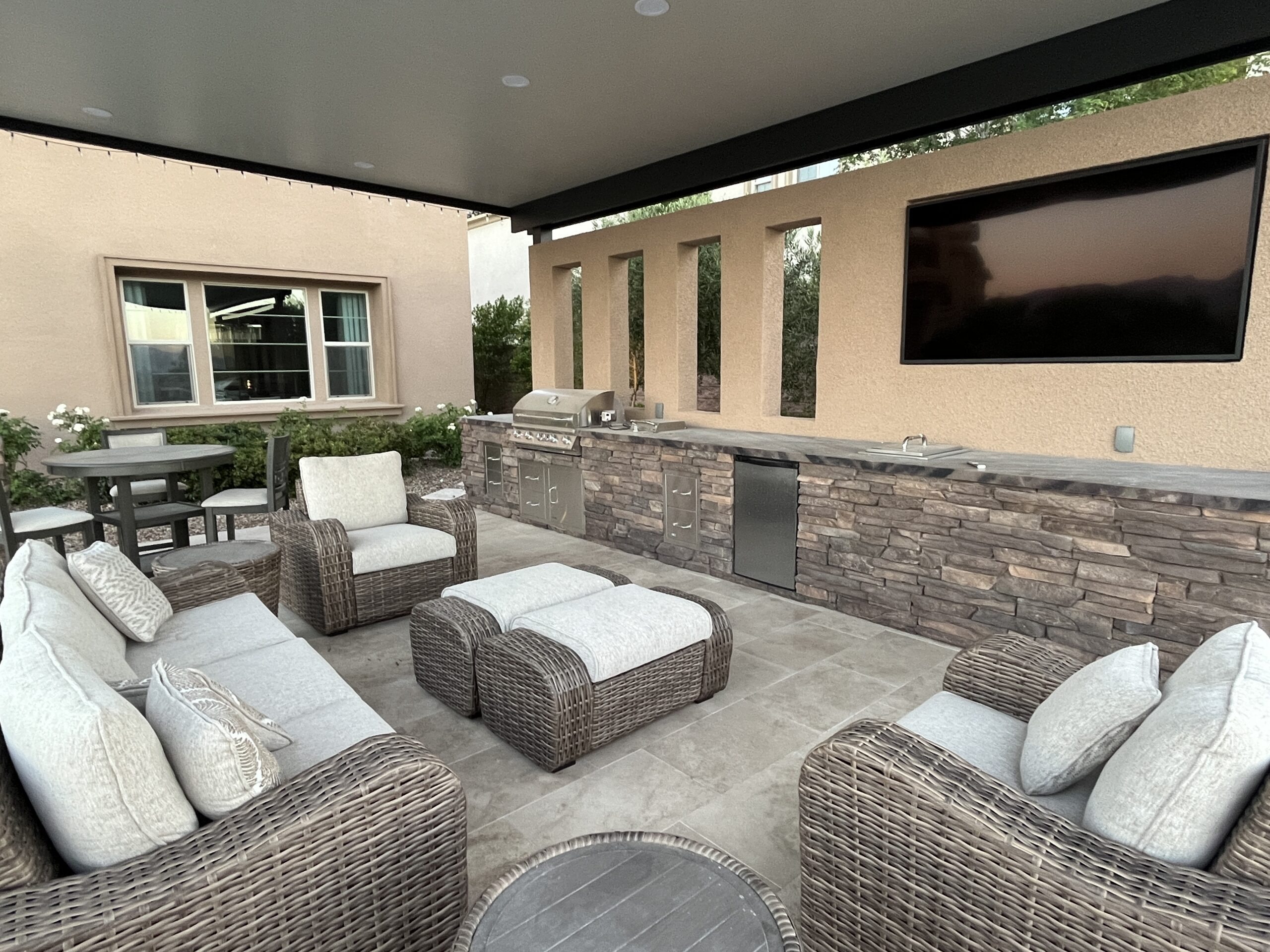 A patio with couches and chairs, television on the wall.
