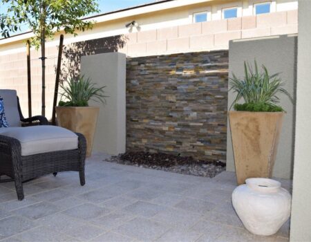 A patio with a stone wall and two large planters.